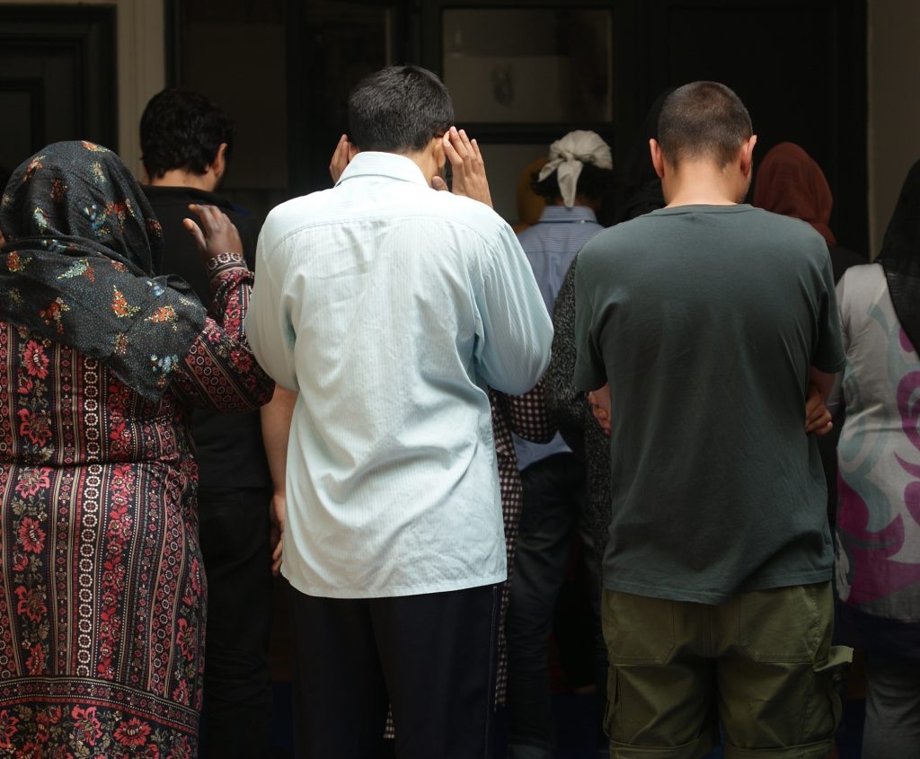 A diverse group of people, of all genders in prayer together